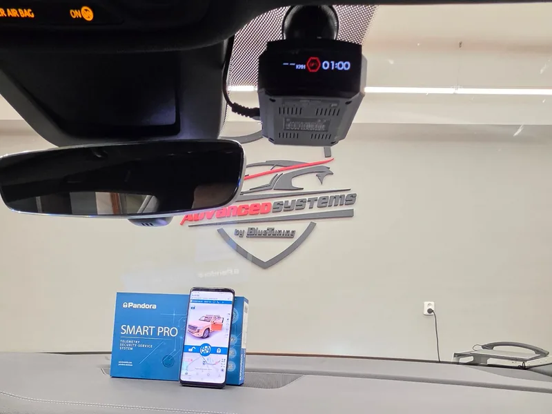 Genevo Max u zpětného zrcátka a telefon s aplikací Pandora v Audi Q8.
