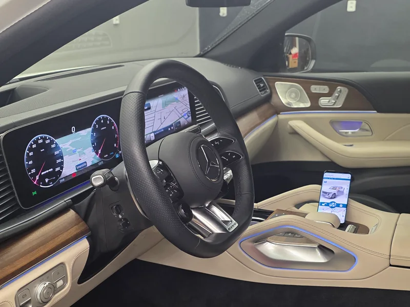 Interiér Mercedesu-AMG GLE 43 s volantem, přístrojovou deskou a aplikací Pandora na telefonu.